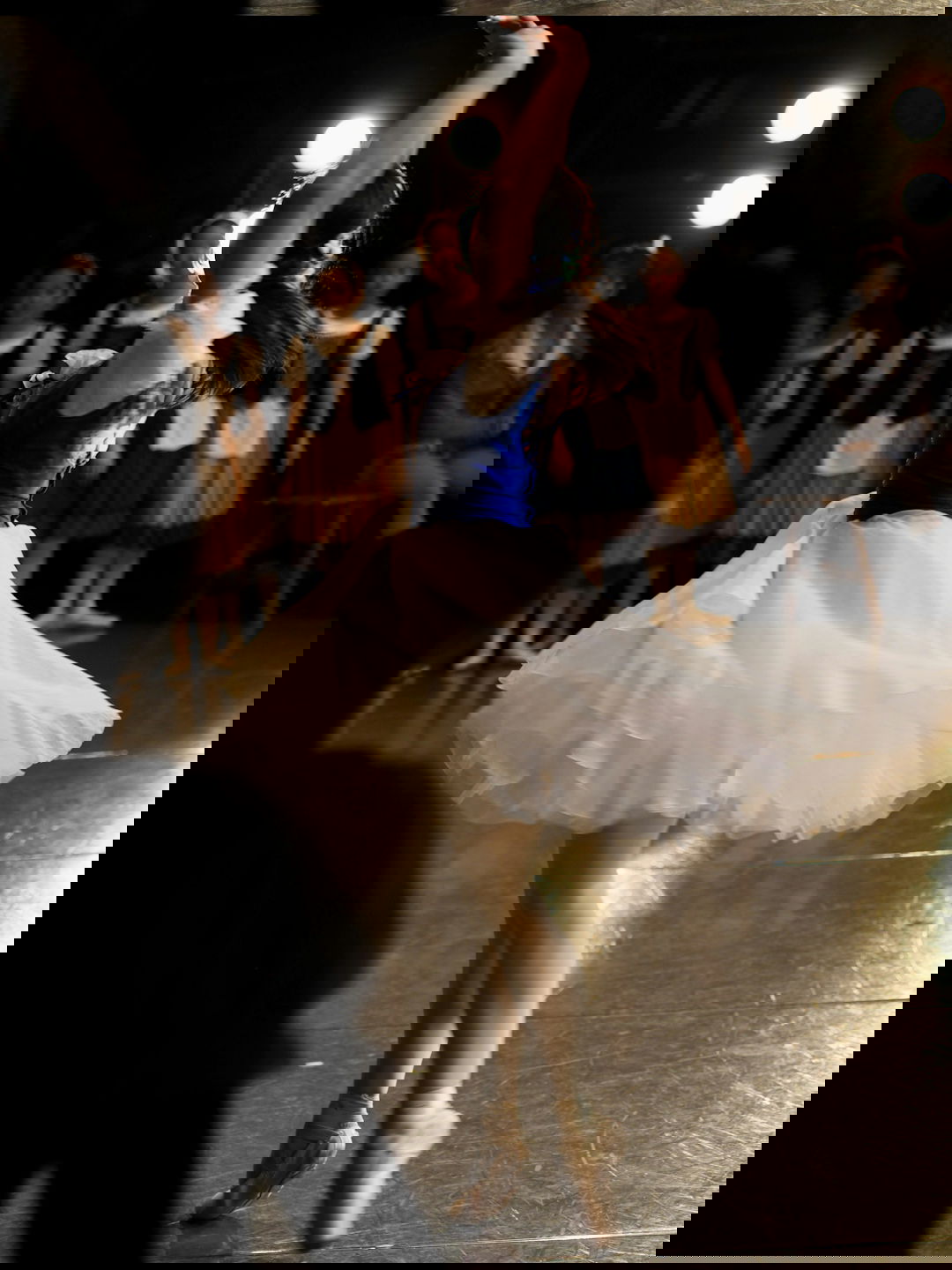 a young girl in a white tutu dancing on a stage